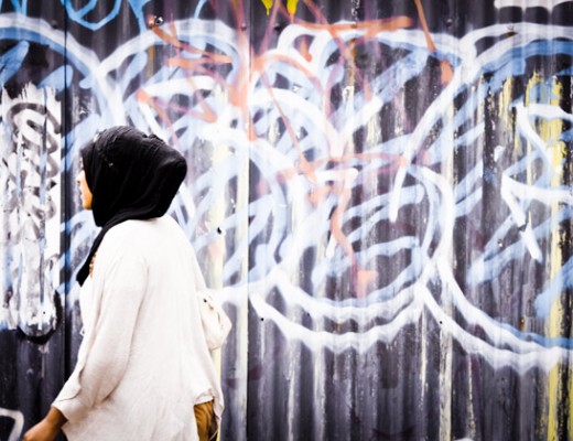 woman walking past graffitti - brick lane, london